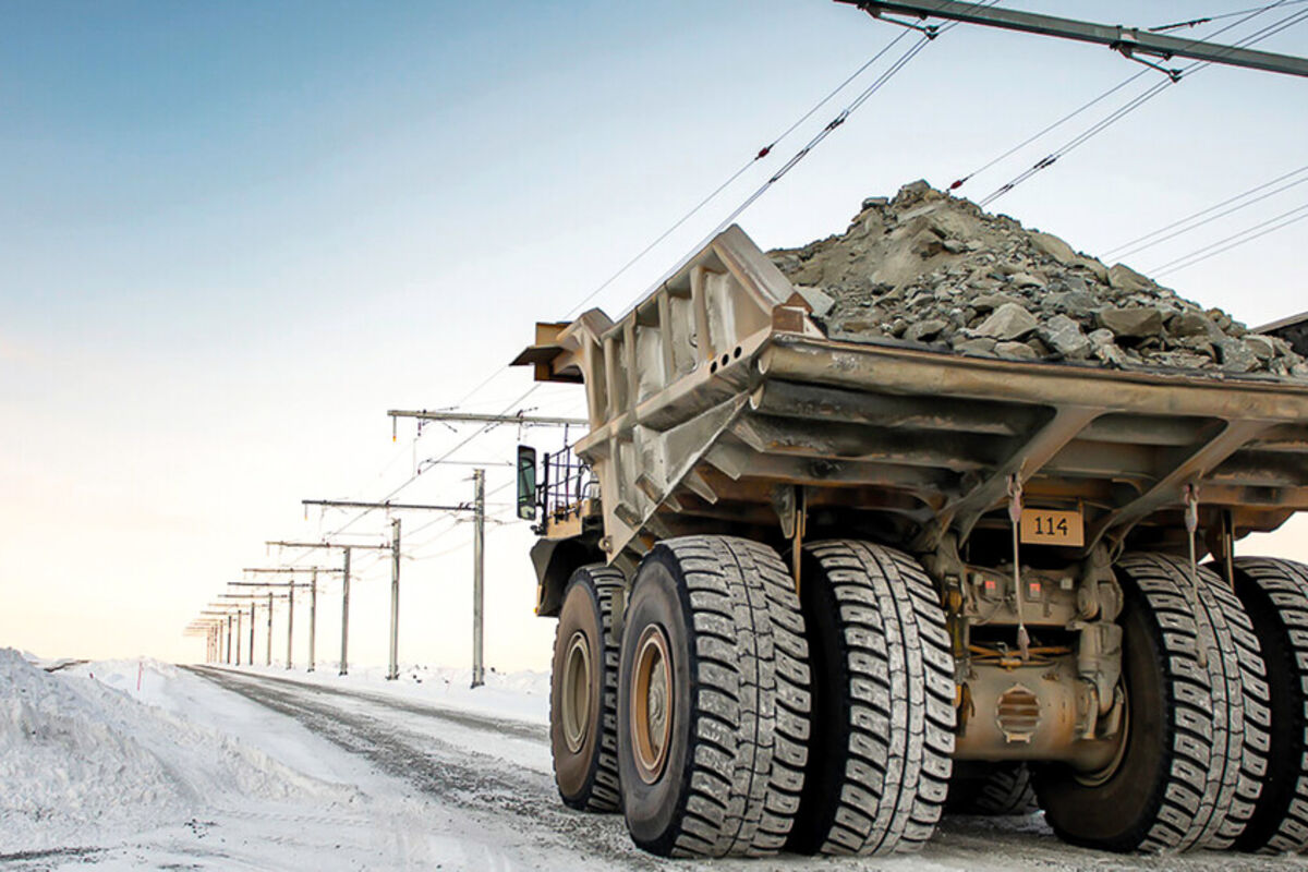 A mining truck loaded with rock being helped up a slope with an overhead trolly.
