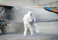 Technicians paint a plane with various coatings to protect it from corrosion.