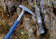 A geologist’s hammer next to lens of graphite at Graphite Creek in Alaska.