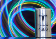 A Tesla 4860 lithium-ion battery with a backdrop of brightly colored swirls.