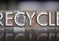 The word recycle stamped in all capital letters on tarnished steel blocks.