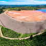 Massive earthen dam holds back red mud tailings at aluminum mine in Brazil.