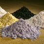 Six piles of white, yellow, grey, and black rare earth oxide powders.