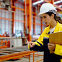 Young female worker with hard hat and PPE in a warehouse setting.