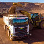 A Cat loader dumps iron ore into a Scania autonomous mining truck.