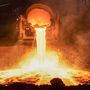 A giant vat of molten steel slag pouring into a pit.