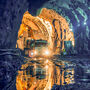 A truck driving into a larger cavern from a tunnel underground.