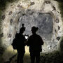 Silhouette of two underground miners collecting data from a mine face.